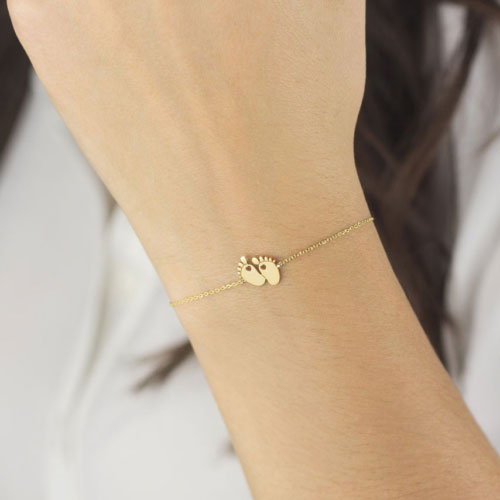 Yellow Gold Charm Bracelet with Tiny Baby Feet Worn By A Woman