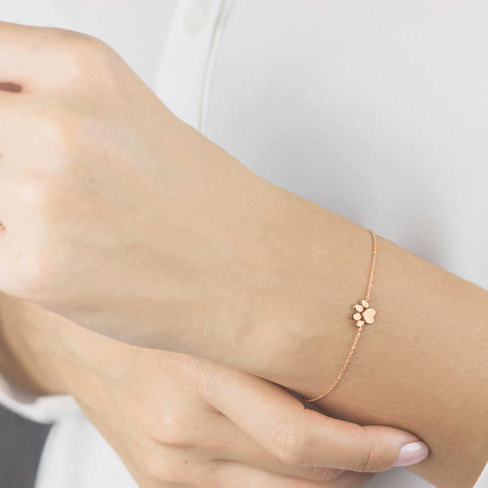 a paw print charm in rose gold Worn By A Woman