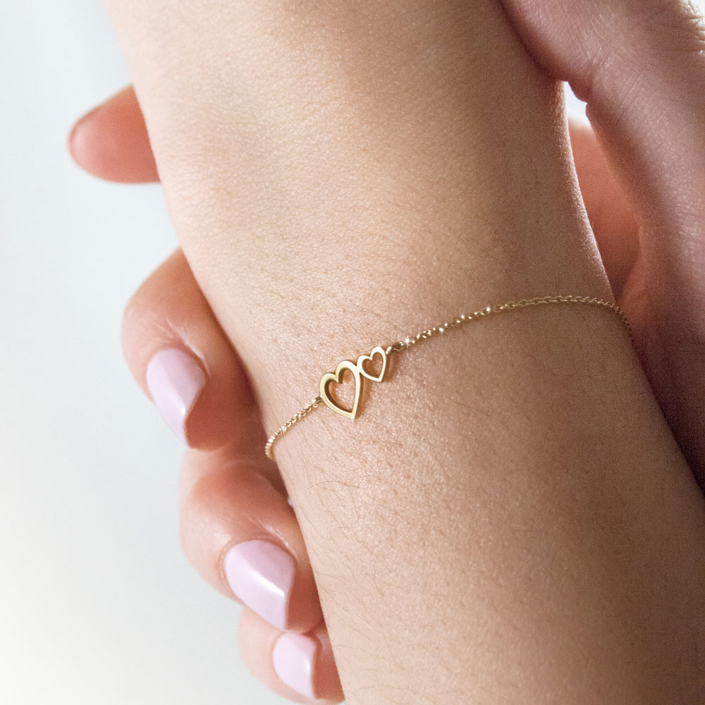 Double Heart Charm Bracelet in Yellow Gold Worn By A Woman