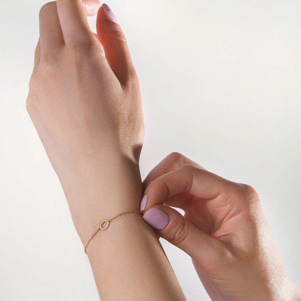Simple Rose Gold Bracelet with a Small Gold Oval Charm Worn By A Woman