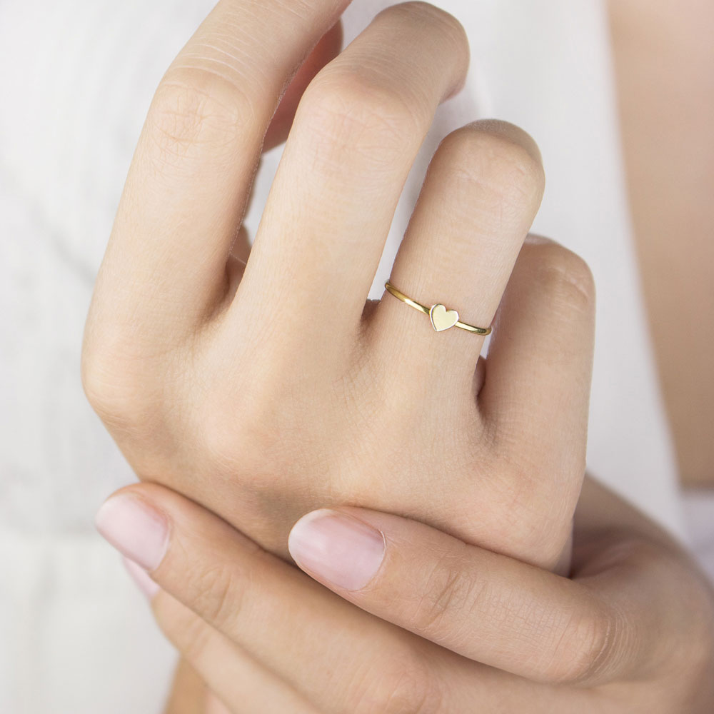 a yellow gold ring with a tiny heart Worn By A Woman