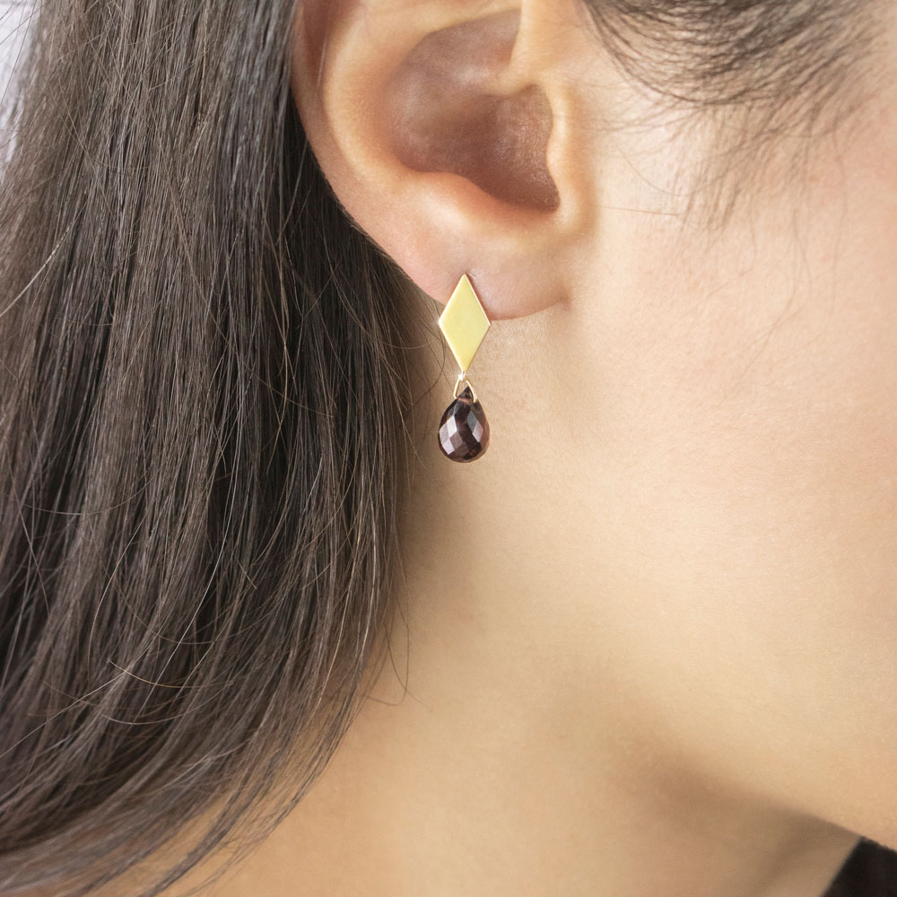 Rhombus Yellow Gold Studs with a Tiny Dangling Garnet Worn By A Woman
