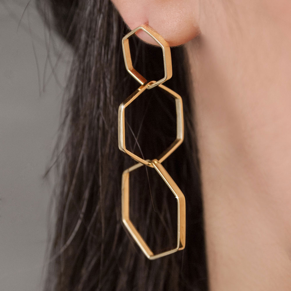 Long Yellow Gold Earrings with Three Dangling Hexagons Worn By A Woman