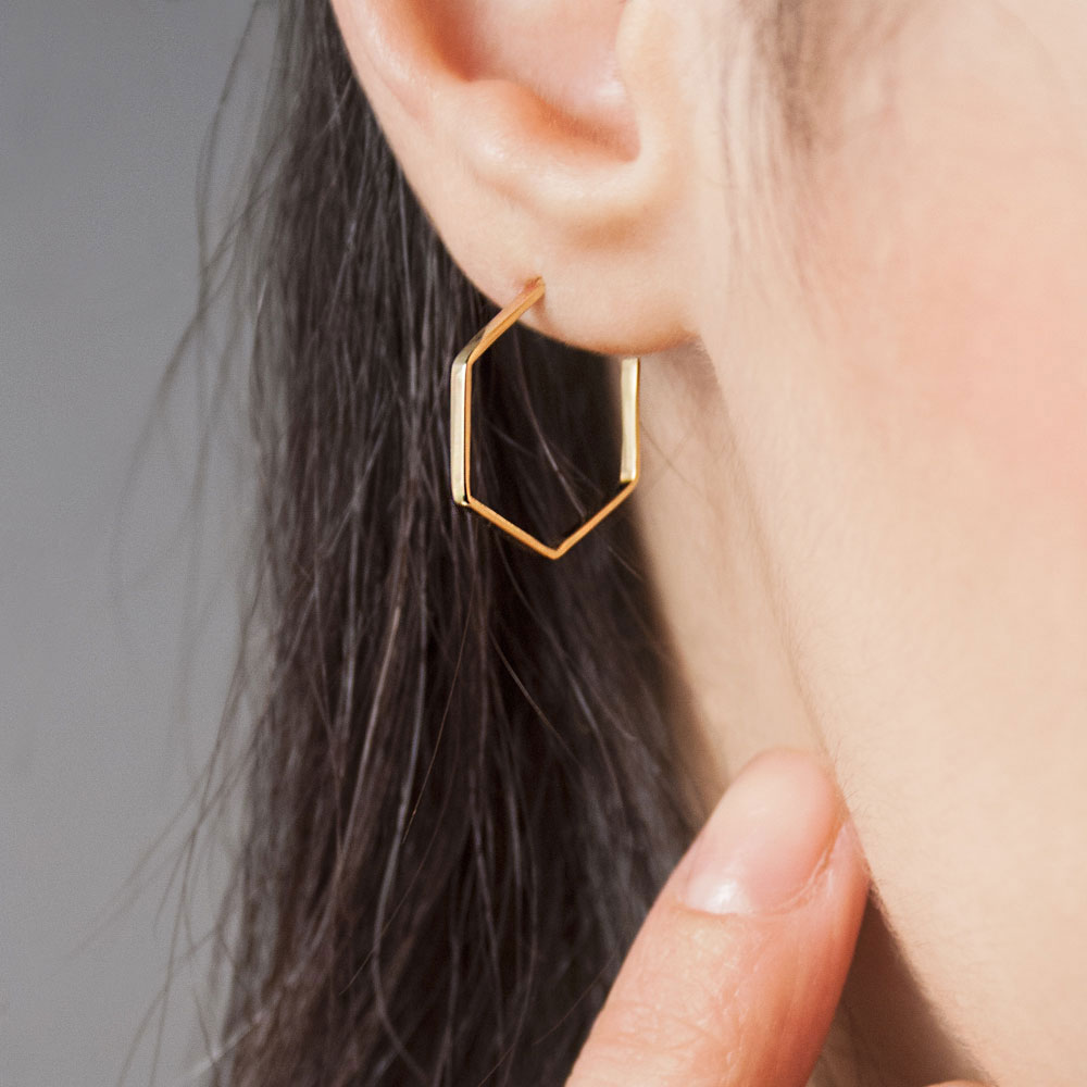 Small Hexagonal Earrings made of Yellow Gold Worn By A Woman