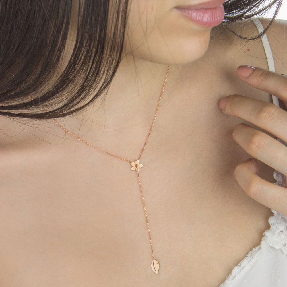 Gold Lariat Style Necklace with a Flower and a Leaf In Rose Gold Worn By A Woman