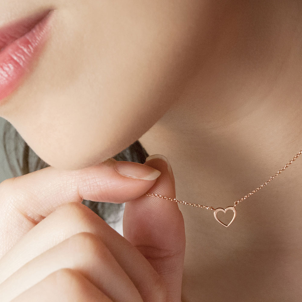 Tiny Heart Charm Necklace made of Rose Gold Worn By A Woman