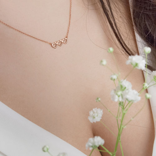Rose Gold Necklace with a Triple Heart Charm Worn By A Woman