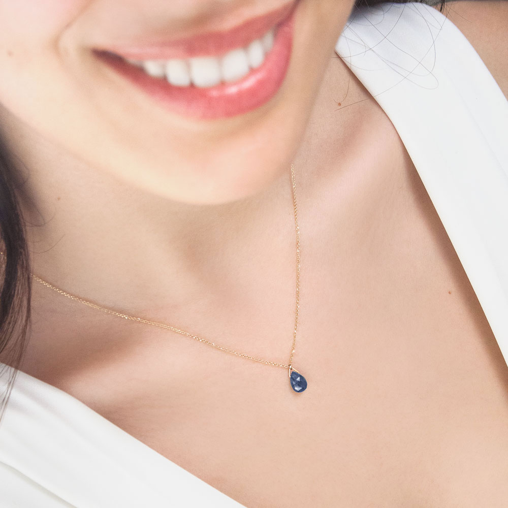 Tiny Sapphire Birthstone Pendant Necklace with a Yellow Gold Chain Worn By A Woman