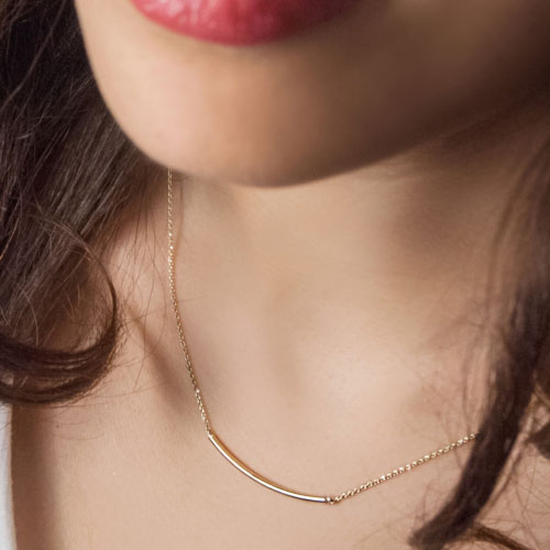 Curved Thin Bar Necklace in Yellow Gold Worn By A Woman
