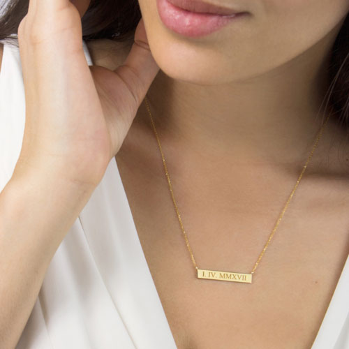 A Roman Numeral Bar Necklace, Personalized In Yellow Gold Worn By A Woman