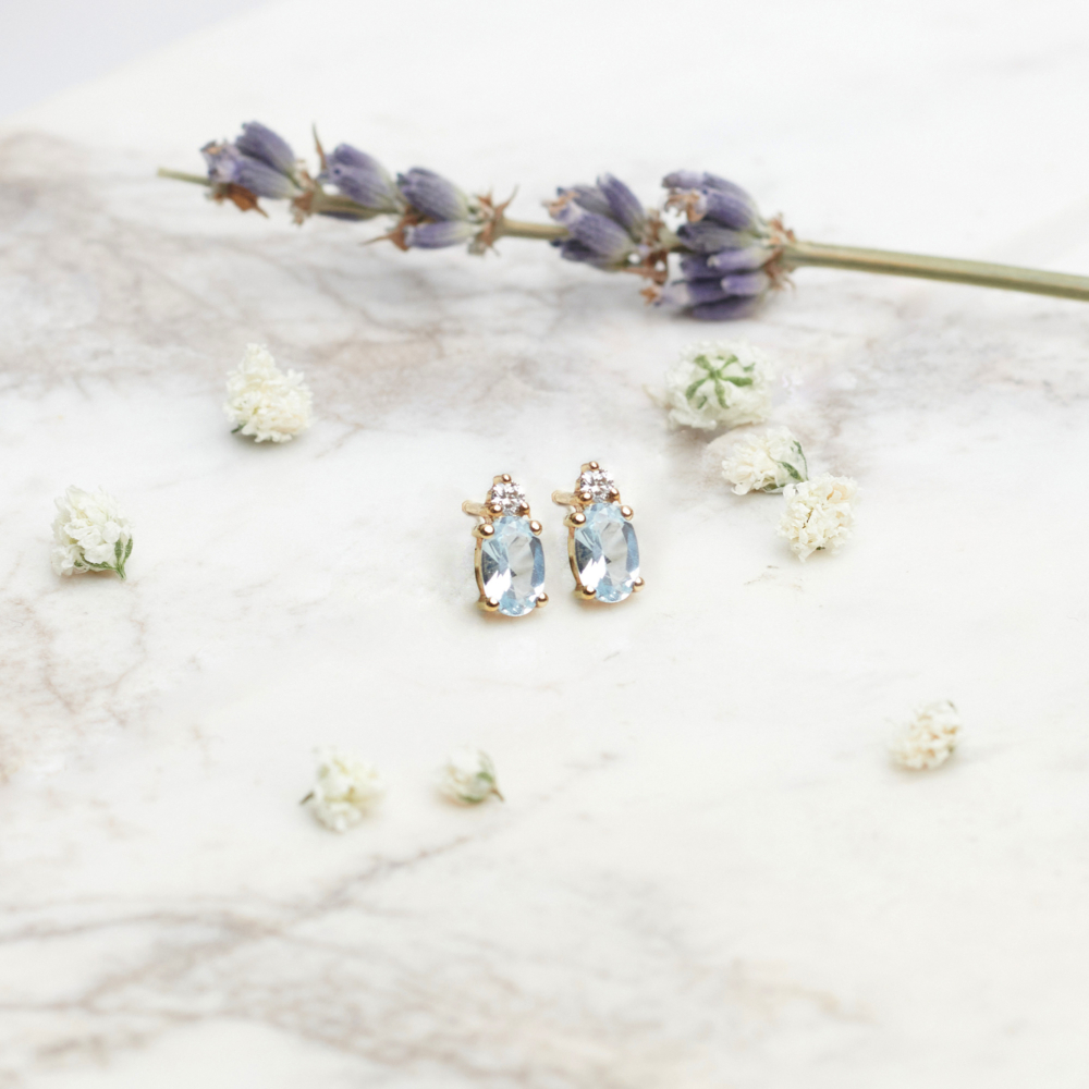 Sky Blue Topaz and Diamond Earrings in Solid Gold on white background with flowers
