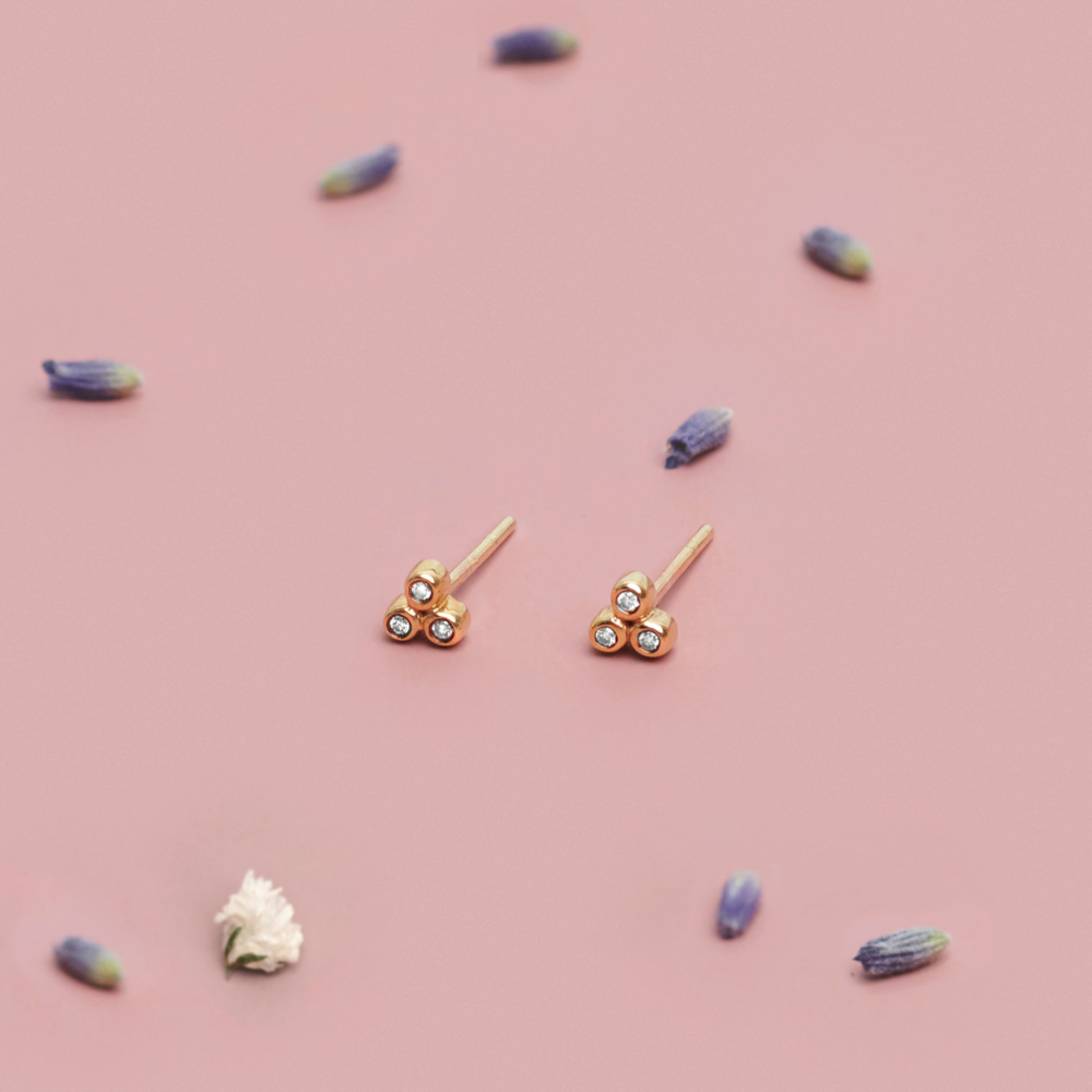 Tiny Diamond Stud earrings in Solid Gold with a pink background