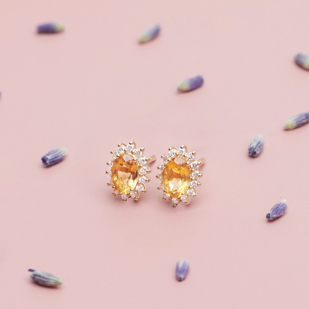 Oval Citrine and Diamonds Earrings in Solid Gold on a pink background with flowers
