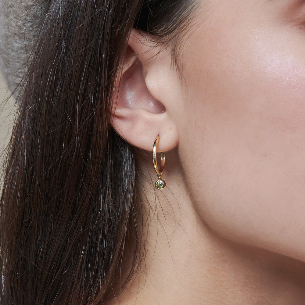 Dainty Gold Hoop Earrings with Tiny Peridots worn by a woman