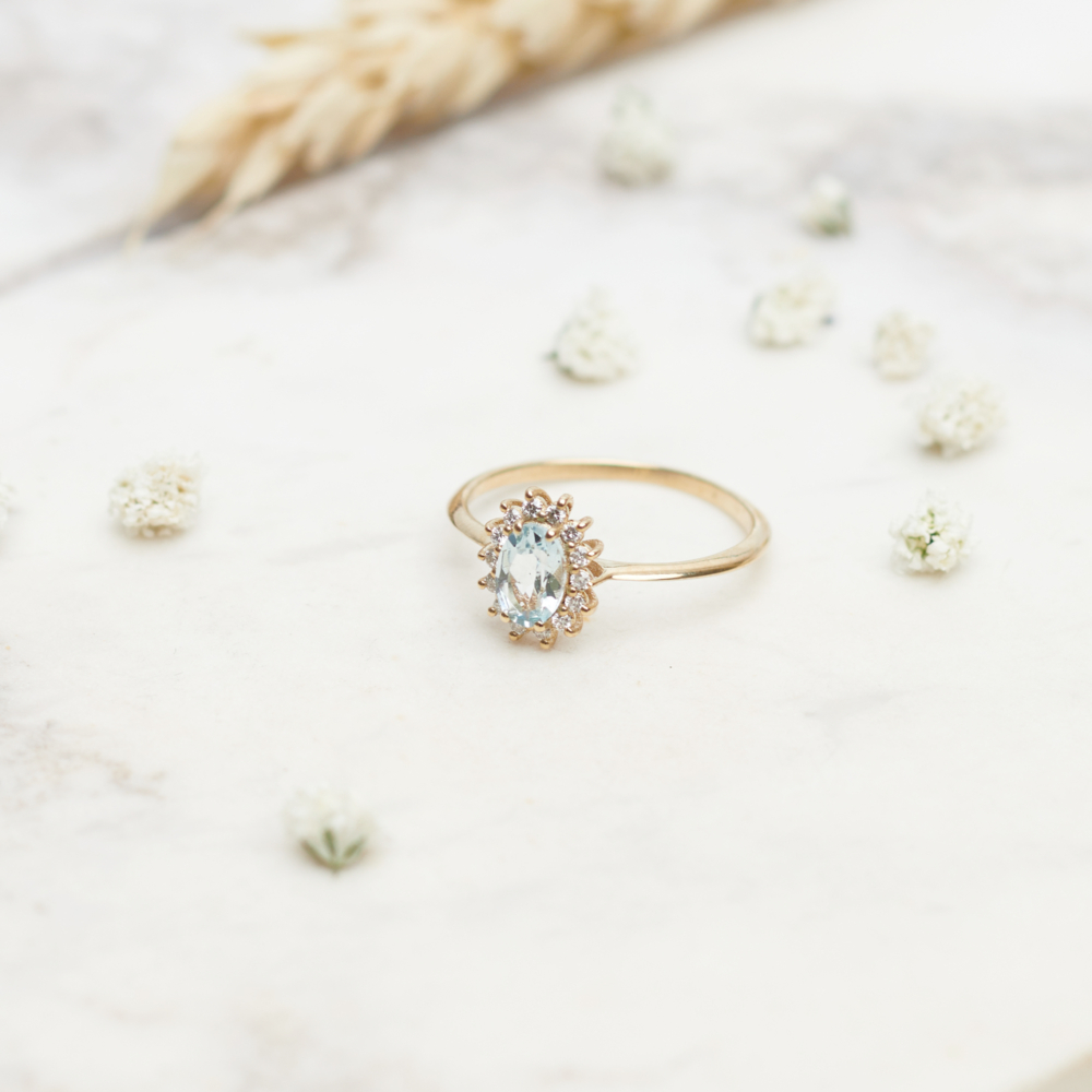An aquamarine ring with tiny diamonds ring in solid gold on a white background