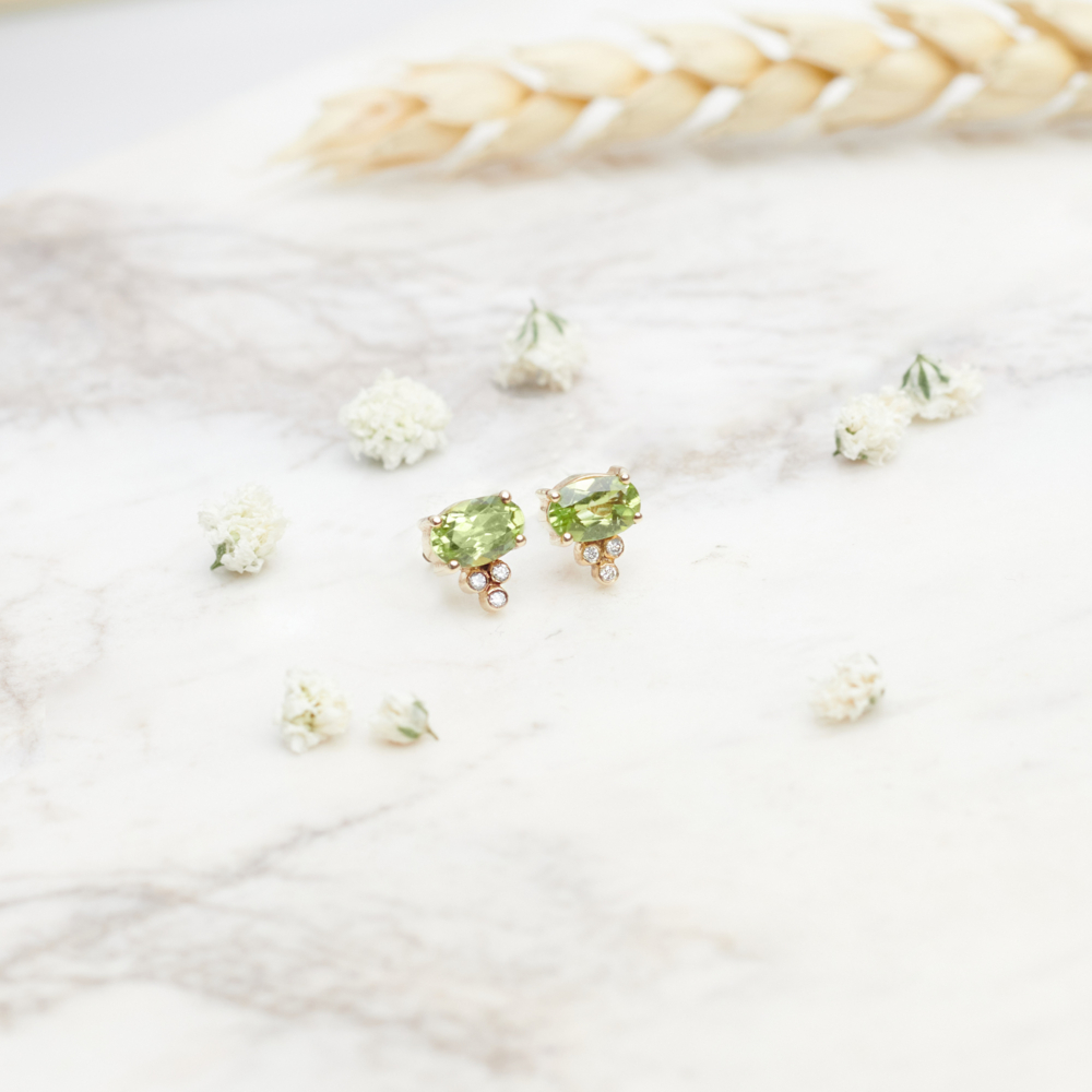 Lime Green Peridot and Diamond Earrings in Solid Gold on a white background with flowers