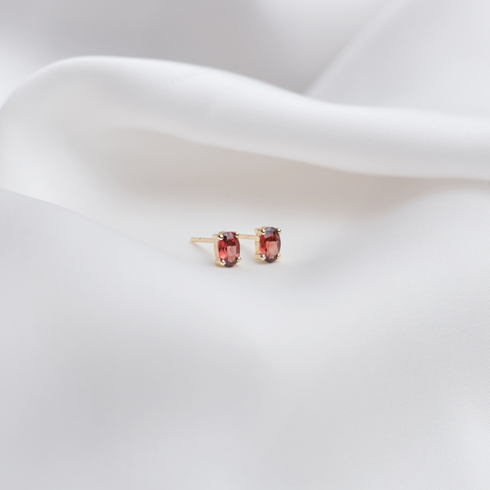 Small Oval Garnet Stud Earrings in Solid Gold on a sheet