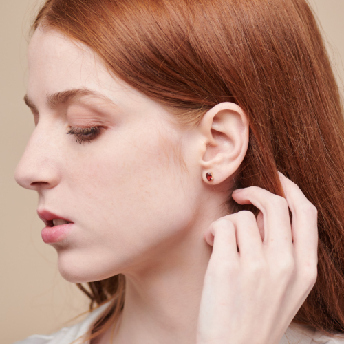Small Oval Garnet Stud Earrings in Solid Gold worn by a woman