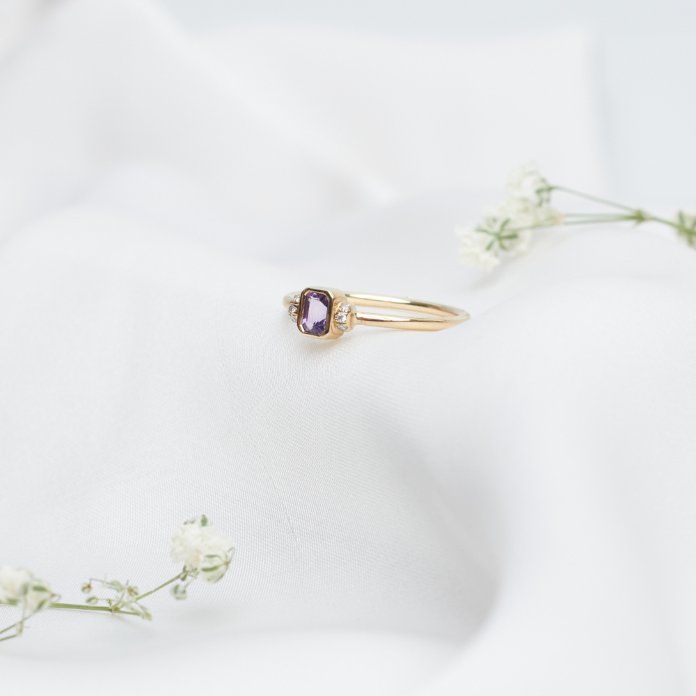 gold ring with amethyst and tiny diamonds on a white sheet