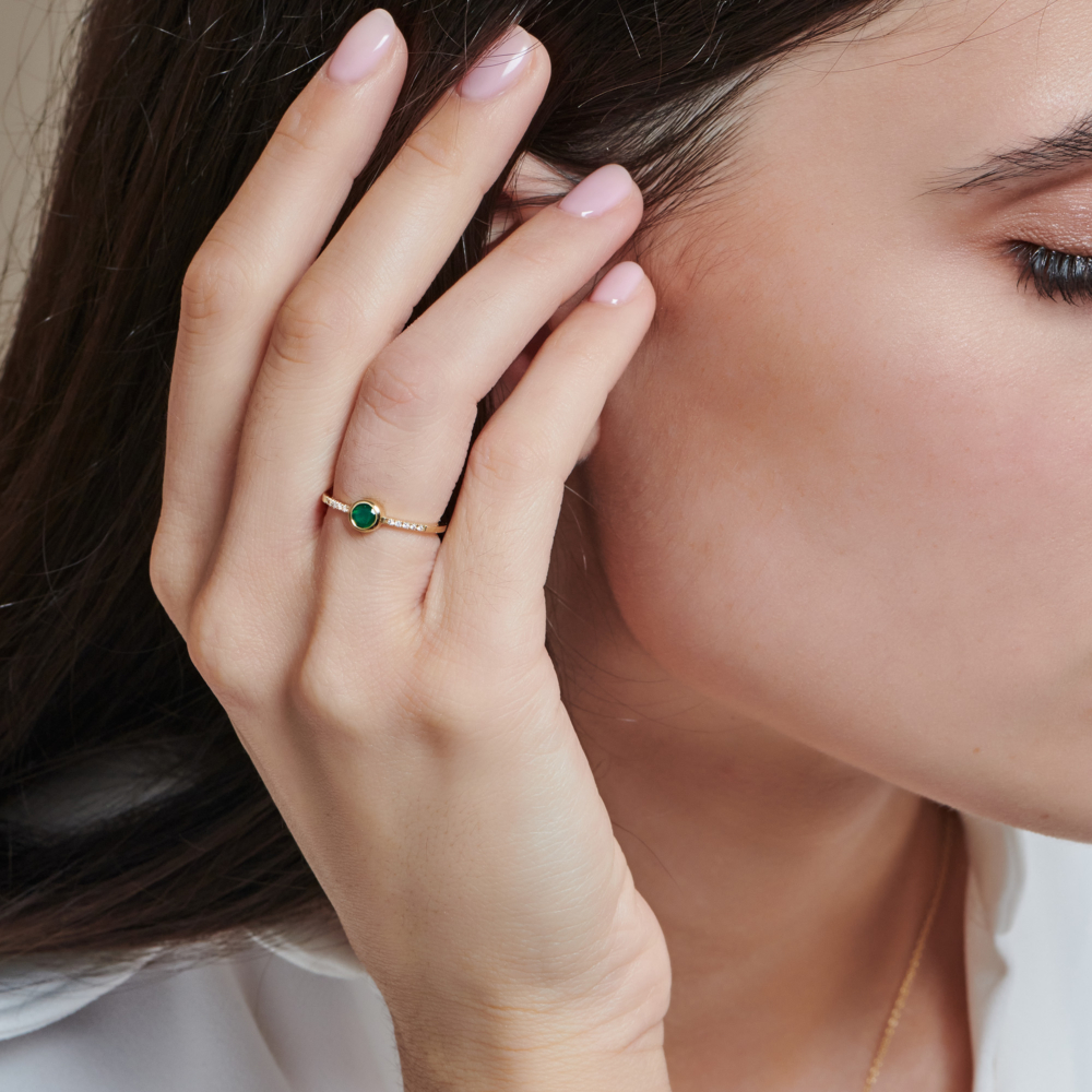 A round green agate and white diamond gold ring. worn by a woman