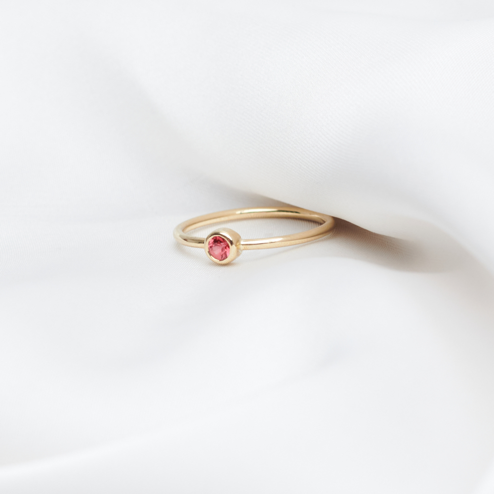 red sapphire solitaire ring in solid gold a white sheet