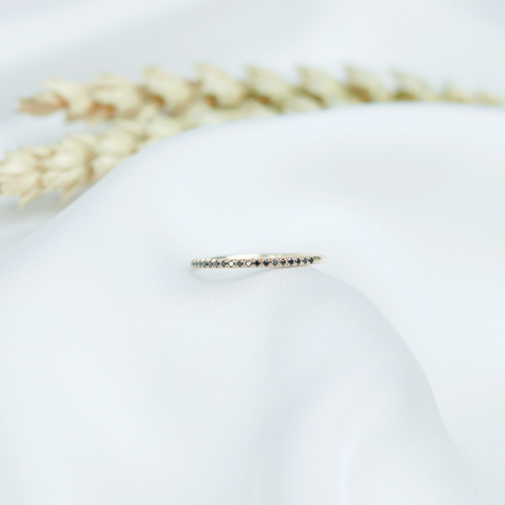 half eternity ring with black diamonds in solid gold on a white sheet