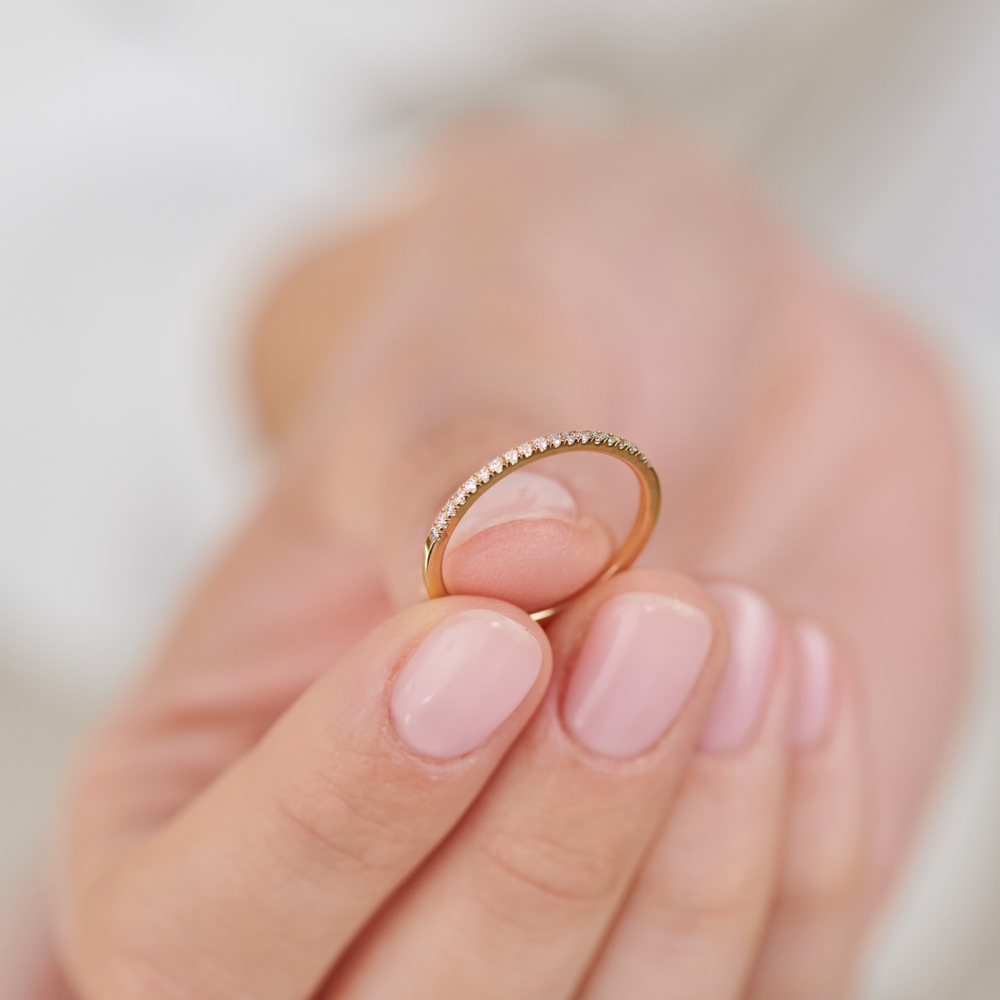 half eternity band ring with white diamonds in solid gold held by a hand