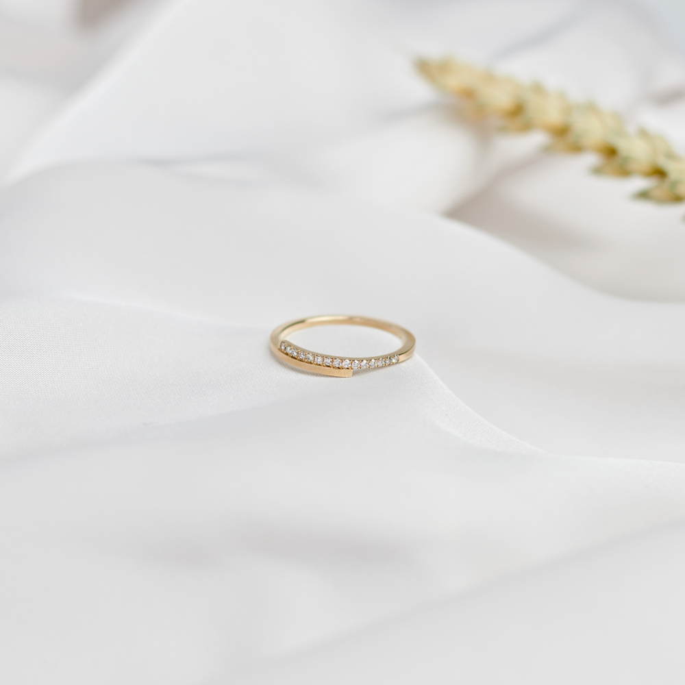 gold wrap ring with white diamonds on a white sheet