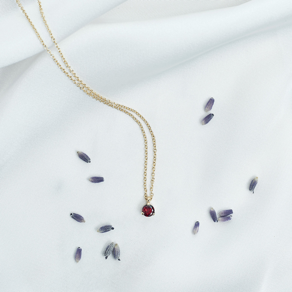Round Garnet Solitaire Necklace in Solid Gold on a white background with pedals