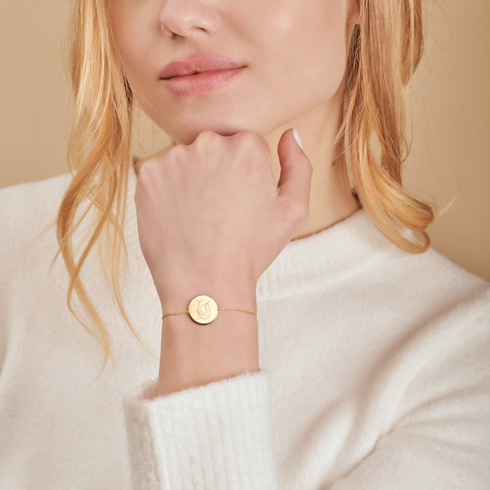 A Holding Hands Charm Bracelet in yellow Gold worn by a female model