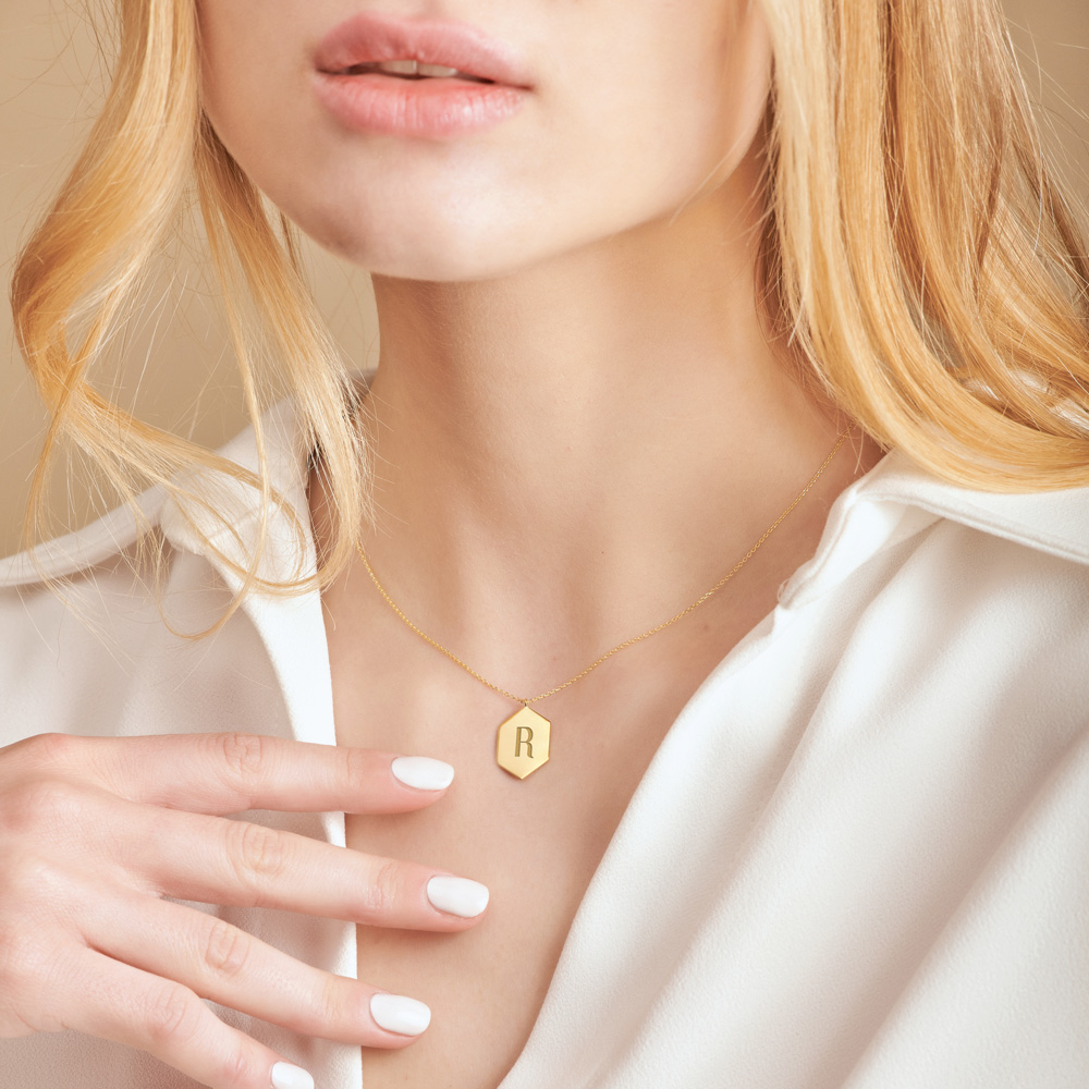 A Hexagon Pendant Necklace with an Engraved Monogram in yellow Gold worn by a female model