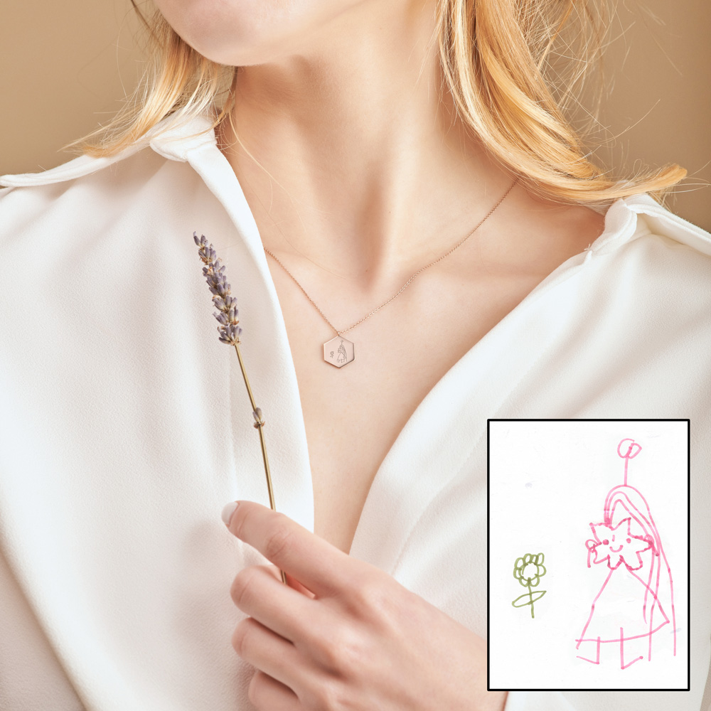 an Engraved, hexagon shaped Child's Drawing pendant Necklace in white Gold worn by a female model